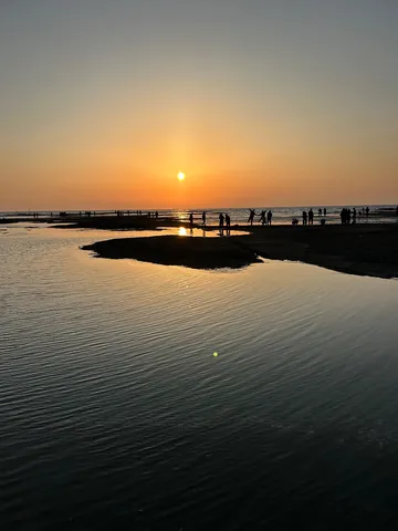 夕暮れの海辺、水面と人影