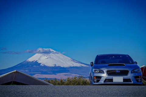 青空に寄り添う雪山と車