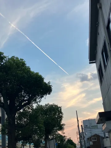 飛行機雲と夕暮れの街並み