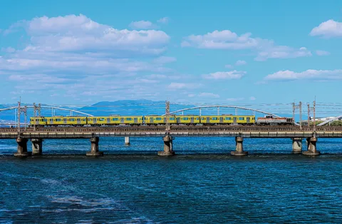 青空と水面を渡る黄色い電車