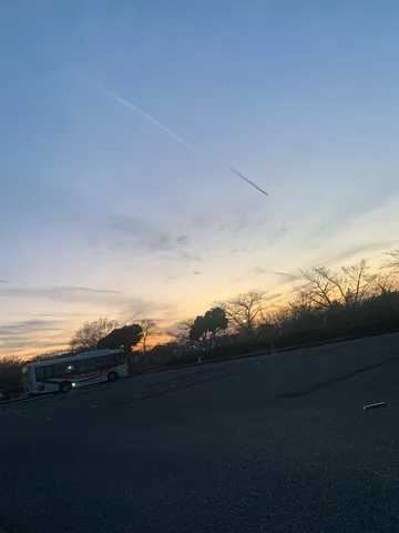 夕暮れに佇むバスと飛行機雲