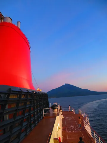 夕暮れの船旅、遠い山のシルエット