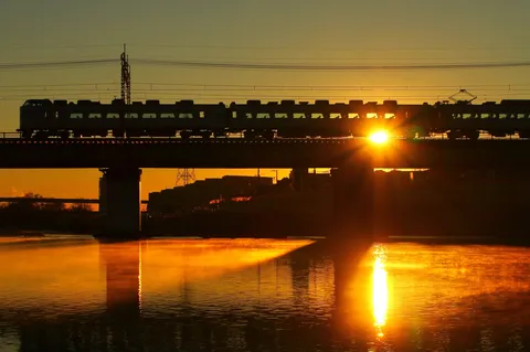 朝焼けに架かる橋を渡る列車