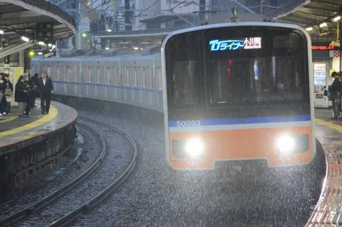 雨の駅、輝くヘッドライト
