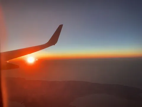 機窓に広がる、空と海と夕陽のグラデーション