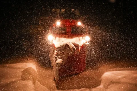 吹雪を照らす除雪車の光