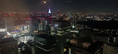 都会の夜空に浮かぶ月と光