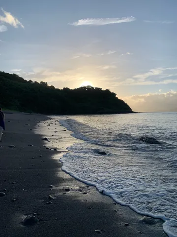 夕暮れの黒い砂浜に寄せる波