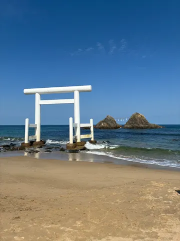 海辺に立つ鳥居、遥か沖には夫婦岩