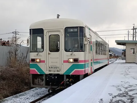 雪のホームに映えるラッピング列車