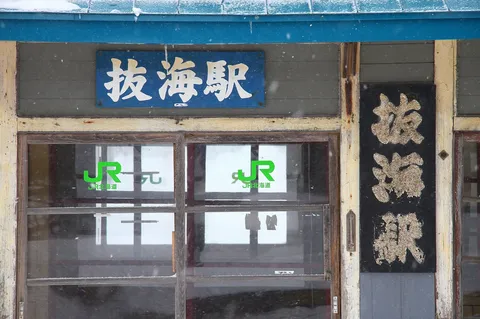 雪降る駅舎、時を刻む看板