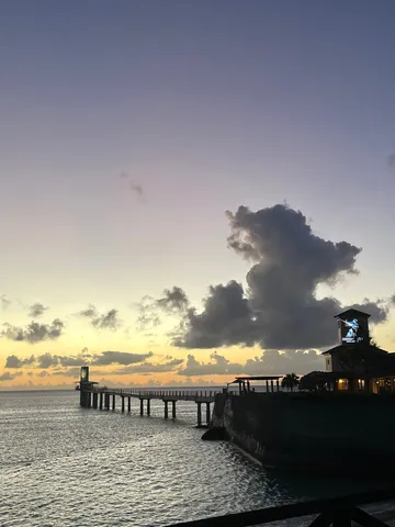 夕暮れの海辺、灯台と桟橋のシルエット