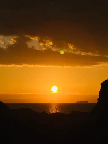 夕暮れの海に浮かぶ貨物船