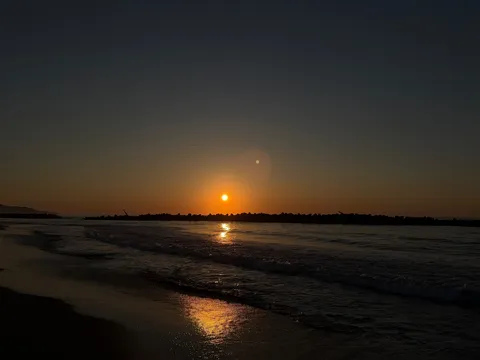 水平線に沈む夕陽、波打ち際のシルエット