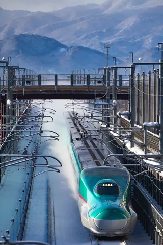 雪煙をまとい疾走する緑の新幹線
