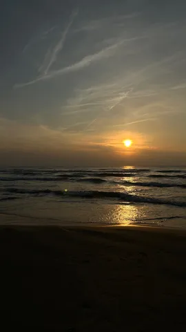 水平線に沈む夕陽、砂浜に灯る光