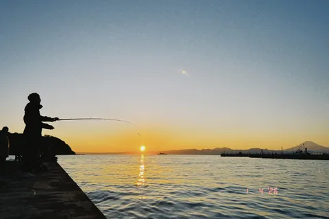 夕暮れの釣り人、山と海