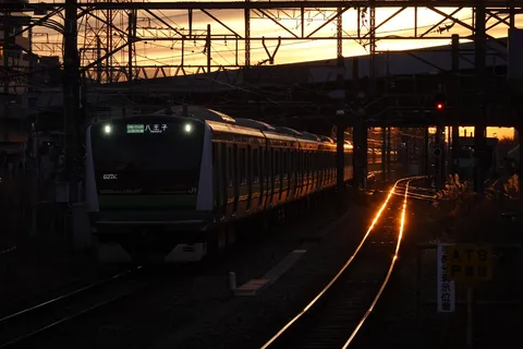 夕陽を浴びて進む、都会の鉄道風景