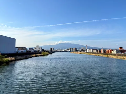 雄大な山と街並みが溶け合う水辺の風景