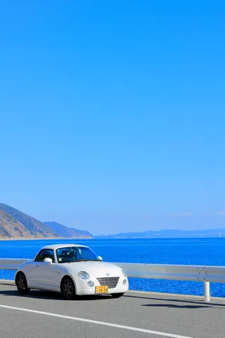 海と道を走る白い車の風景