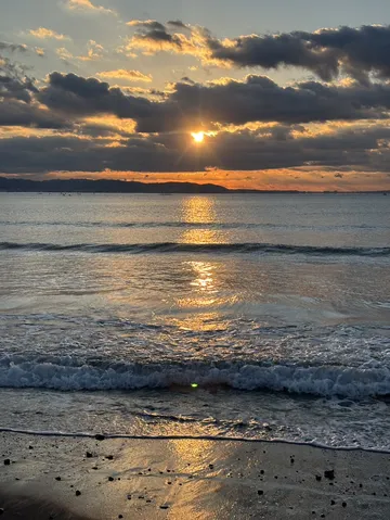 雲間から差し込む夕陽と波打ち際