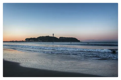 夕暮れの波打ち際、沖に島影