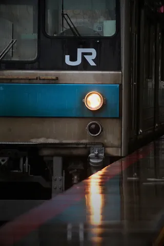 ヘッドライトが照らす雨の駅