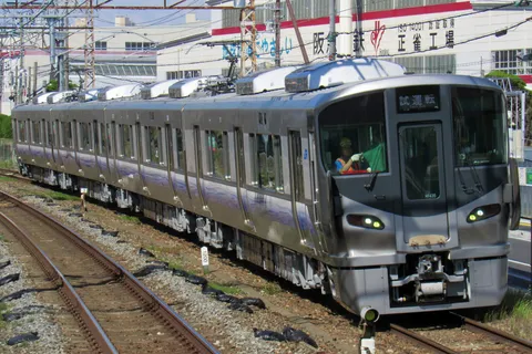 試運転の銀色車両が都市を行く