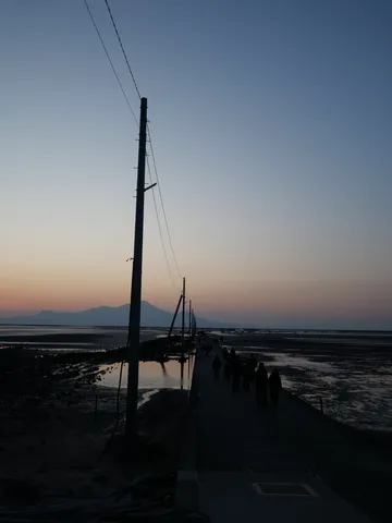 夕暮れの灯台と海辺の道