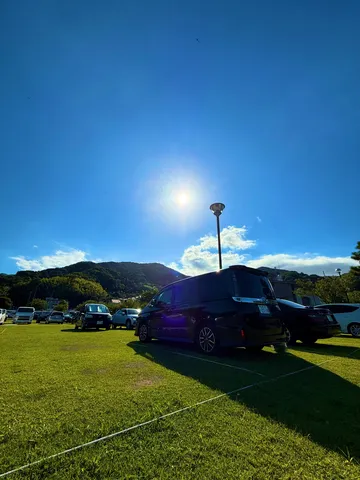 青空と太陽、緑の芝生と車