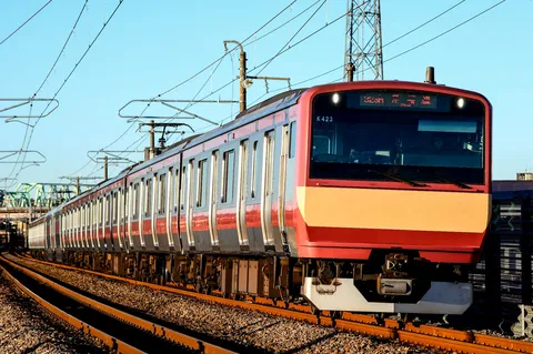 青空と架線、力強く進む列車