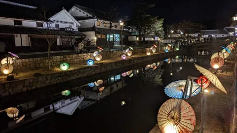 夜の水面に映る傘の灯り