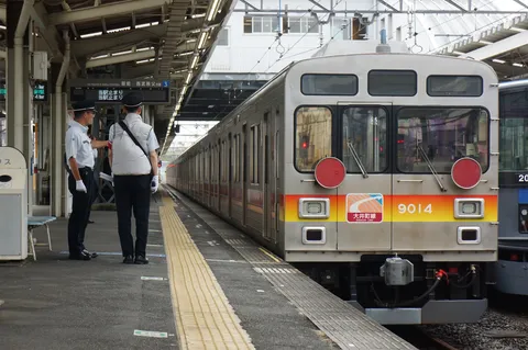朝の駅で動く銀色の列車