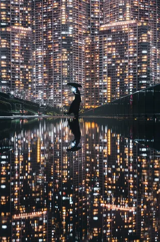 光るビルと雨の夜、傘を差す人