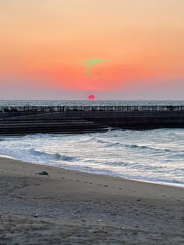夕暮れの海辺、茜色の空と波