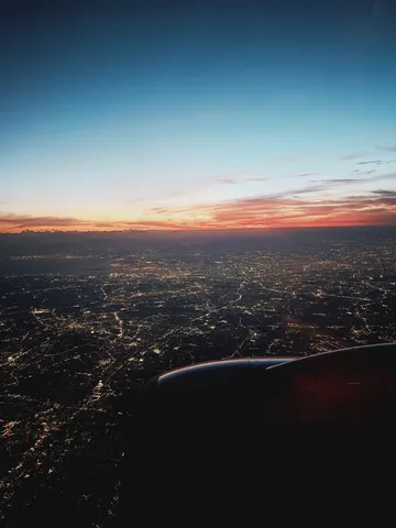 夜景に沈む空と飛行機雲