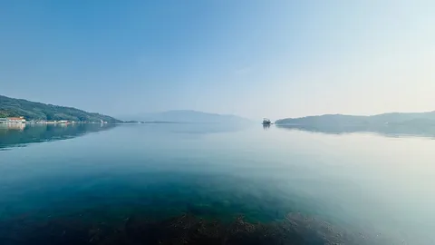 静寂の湖面と遠くの船