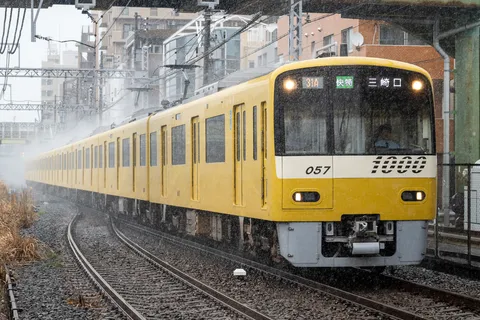 雪煙を上げる黄色い電車