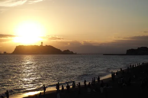 沈む夕陽と海辺の人影