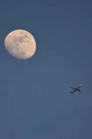 月と飛行機の青空共演