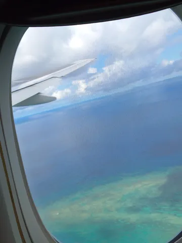 窓から覗く、青い海と飛行機雲
