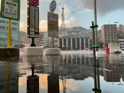 雨上がりのバス停、水面に映る街
