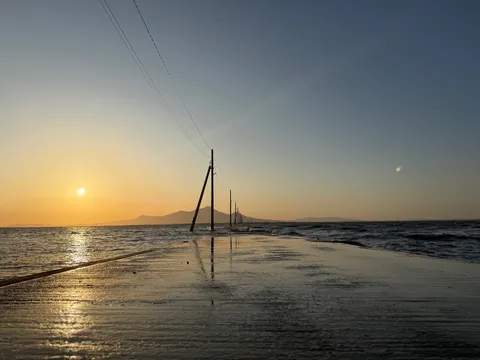 波間に続く電柱と夕焼け
