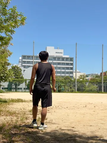 晴れやかな空の下、テニスコートに立つ君