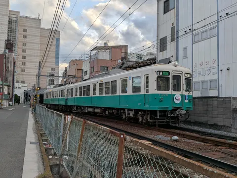 電線の街を走る緑の車体