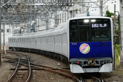 電線の迷路を抜ける青い列車
