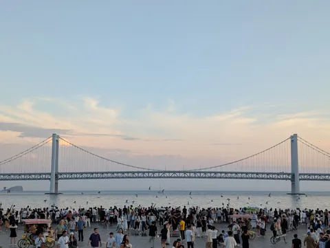 夕暮れの海辺、人々と橋のシルエット